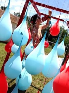 a woman is standing next to some blue and red vases hanging from the ceiling