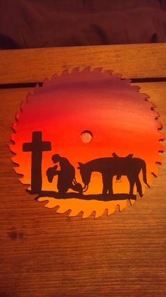 a wooden box with a cutout of two horses and a man kneeling at the cross