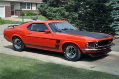 an orange mustang parked in front of a house