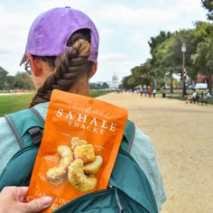 a woman holding a bag of sahale snacks in front of her back to the camera