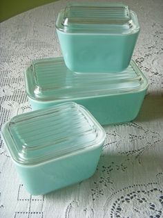 three glass containers sitting on top of a white tablecloth covered table with doily