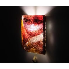 a lamp that is on the side of a wall with a red and yellow shade