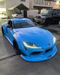 a blue toyota sports car parked in front of a building with other cars behind it