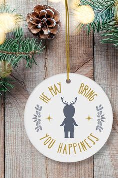 a christmas ornament hanging on a wooden table with pine cones and evergreen branches