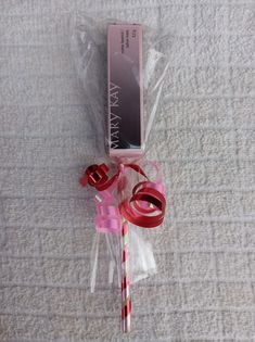 a candy cane wrapped in cellophane and tied with pink ribbon on a bed