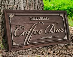 a wooden sign sitting next to a tree on top of the grass and dirt ground