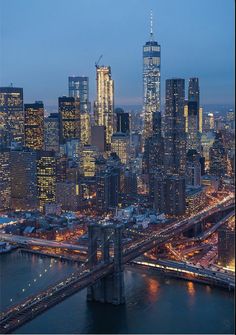 the city skyline is lit up at night, with skyscrapers and bridges in the foreground