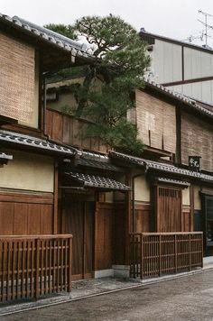 an old building with wooden shutters and trees on the side walk in front of it