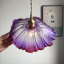 a hand holding a purple light hanging from a ceiling