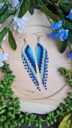 two pairs of blue and white beaded earrings sitting on top of a wooden board