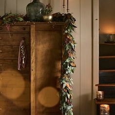 a tall wooden cabinet sitting next to a stair case filled with candles and greenery