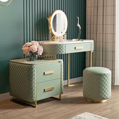 a dressing table with a mirror, stool and flower arrangement in front of green wall