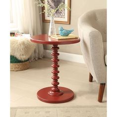 a red table with a bird figurine sitting on it's top next to a chair