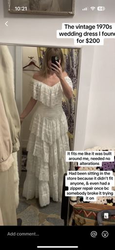 a woman taking a selfie in front of a mirror wearing a white wedding dress