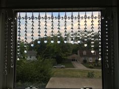 an open window with glass beads hanging from it's sides and cars parked in the driveway