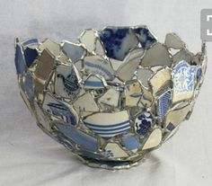 a bowl made out of broken glass on a white tableclothed surface with blue and white designs