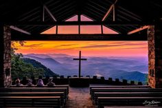 people are sitting in pews at the top of a hill with a cross on it