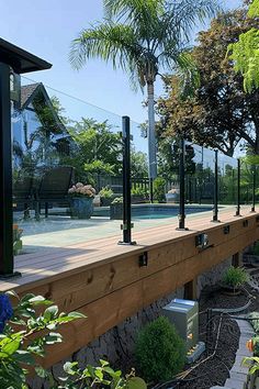 an outdoor tennis court surrounded by trees and plants on the side of a wooden deck