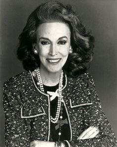 an old photo of a woman in a suit and pearls on her lapel, smiling at the camera