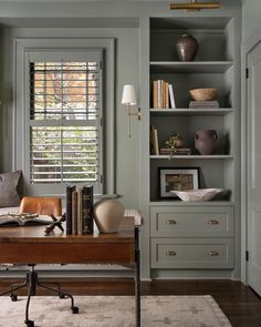 an office with bookshelves, desk and lamp in it's center area