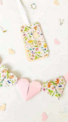 paper hearts and tags on a white surface with confetti scattered around them in the background