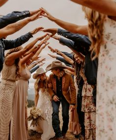 a group of people standing around each other with their hands in the air and wearing cowboy hats