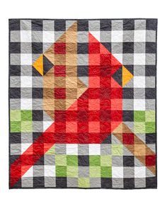 a red bird sitting on top of a black and white checkered quilt