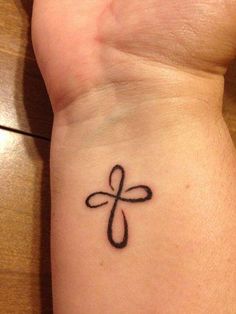 a cross tattoo on the wrist with a bible verse above it that reads, there are since we have been justified through faith, we have peace with god through our