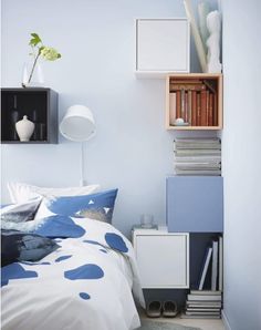 a bedroom with blue and white decor on the bed, bookshelf in the corner