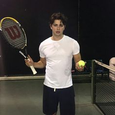 a young man holding a tennis ball and racquet