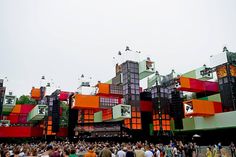 a large group of people standing in front of an orange and green building with lots of windows