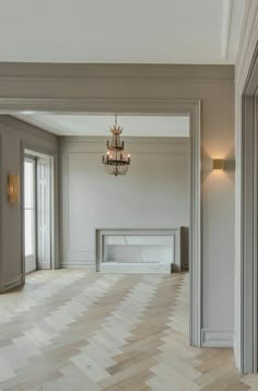 an empty room with wood flooring and chandelier