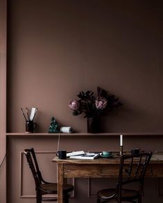 a wooden table sitting under a window next to a vase with flowers on top of it