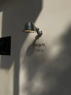 the shadow of a lamp is cast on the wall next to a sign that reads dawn dawn