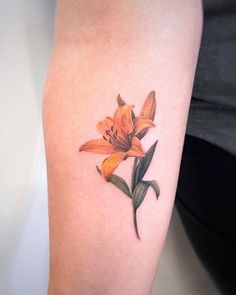 an orange lily tattoo on the arm