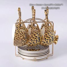 a set of leopard print plates and cups on a metal stand with gold rims