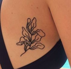 a woman's back with a flower tattoo on her left side ribcage