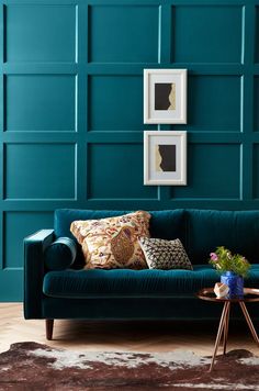 a living room with teal walls and brown rugs on the wooden flooring