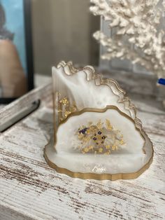 a white and gold ring sitting on top of a wooden table