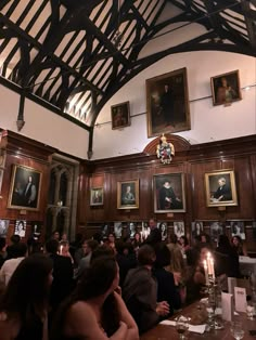 a large group of people sitting at tables in a room with paintings on the walls