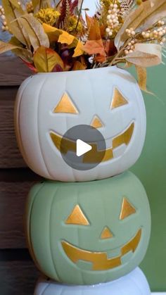 a white pumpkin planter sitting on top of a green container filled with leaves and flowers