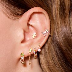 a close up of a person's ear with three different colored stones on it