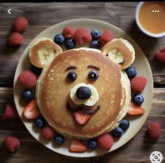 a pancake with fruit on it and a face made to look like a bear