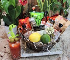 a basket filled with lots of different types of food and drinks next to some plants