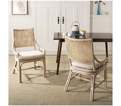 two chairs sitting at a table with a tea kettle on top of it in front of a white door