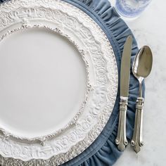 an empty white plate with silverware on it next to a blue and white napkin