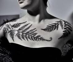 a woman with a tattoo on her chest is looking off to the side and has leaves