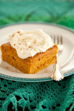 a white plate topped with a piece of cake next to a fork and green table cloth