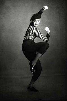 black and white photograph of a woman in striped shirt doing a dance move with her hands up