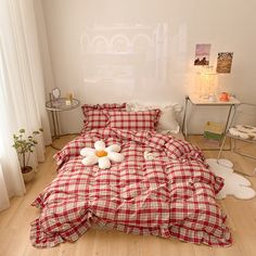 a bed with red and white checkered comforter on it in a bedroom next to a window